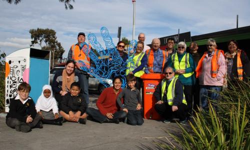 A group of 17 community members, children and adults, some wearing hi-vis clothing 